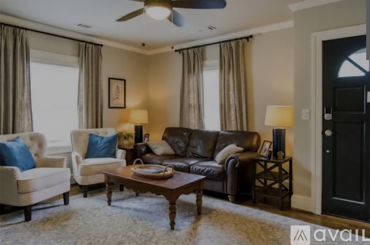 A living room with a brown leather couch, a wooden desk with a computer, and a television.
