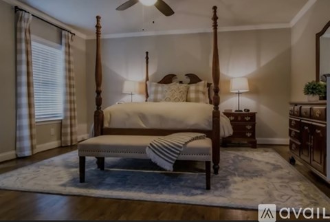 A bedroom with a four poster bed and a rug on the floor.