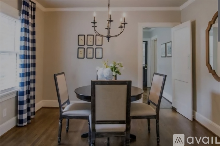 A dining room with a table set for four and a chandelier.
