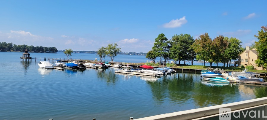 A serene lake with boats docked at a pier and a house in the distance.