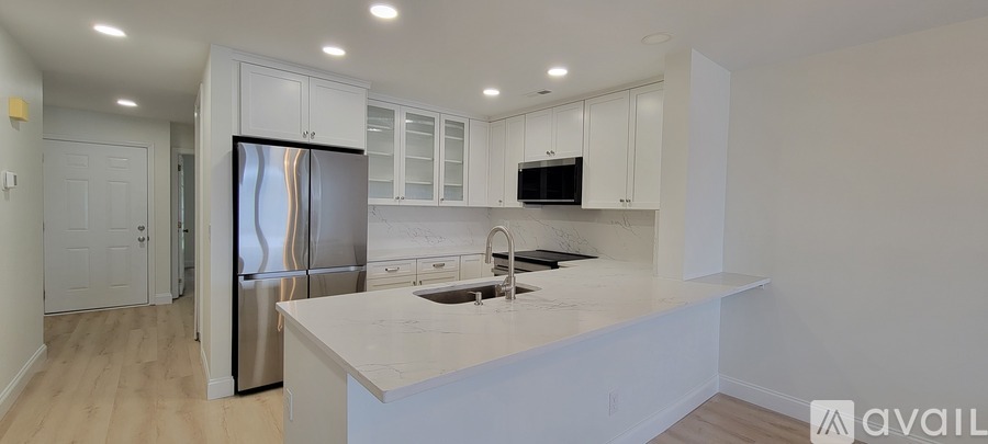 A kitchen with white cabinets and a stainless steel refrigerator.