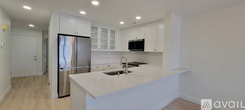 A kitchen with white cabinets and a stainless steel refrigerator.