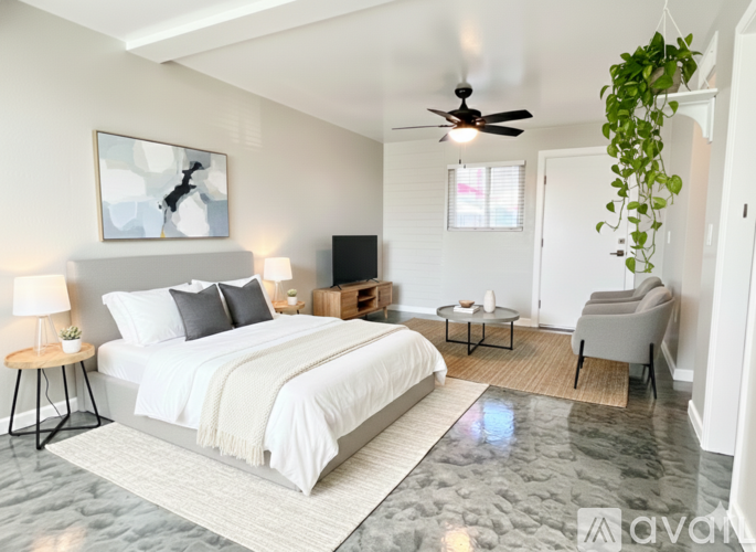 A bedroom with a large bed, a ceiling fan, and a chair.