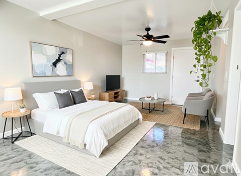 A bedroom with a large bed, a ceiling fan, and a chair.