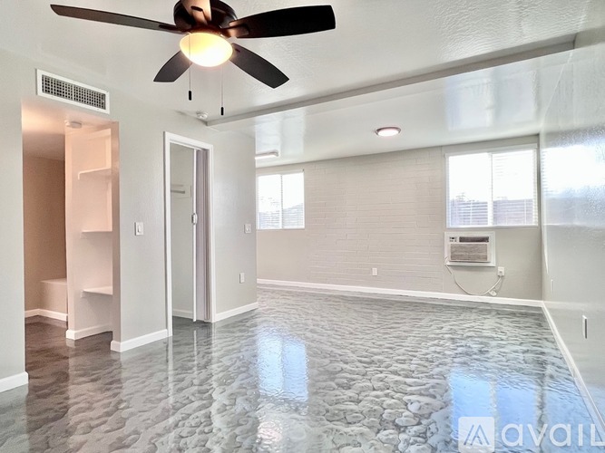 A spacious room with a ceiling fan and stone tile flooring.