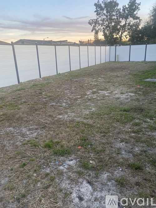 A long white fence runs along the edge of a grassy field.