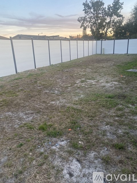 A long white fence runs along the edge of a grassy field.