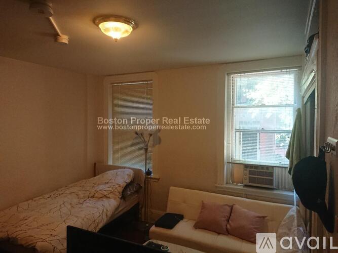 A bedroom with a bed, a couch, and a window.