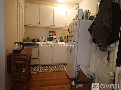 A kitchen with a refrigerator, cabinets, and a counter.