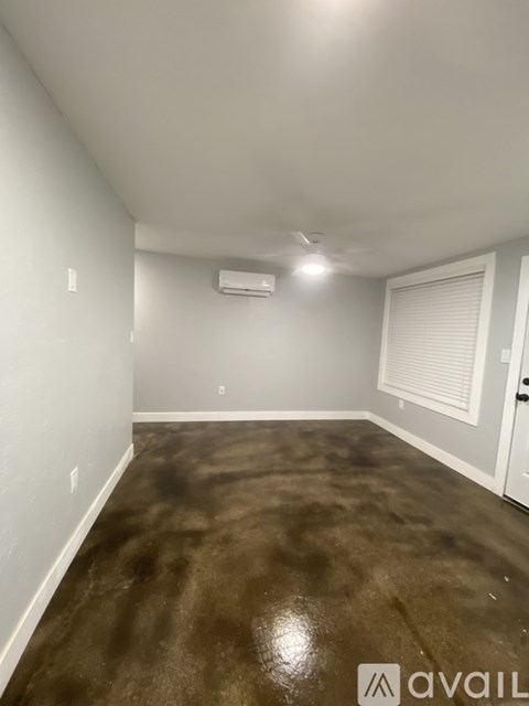 A room with a brown floor and a white wall with a window.