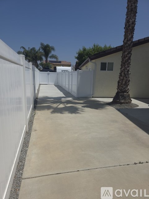 A white fence runs along the side of a concrete walkway.