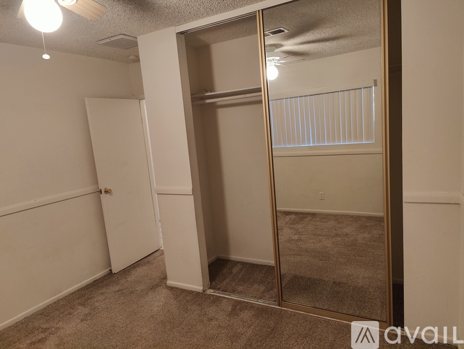 A bedroom with a white door and a mirror on the wall.