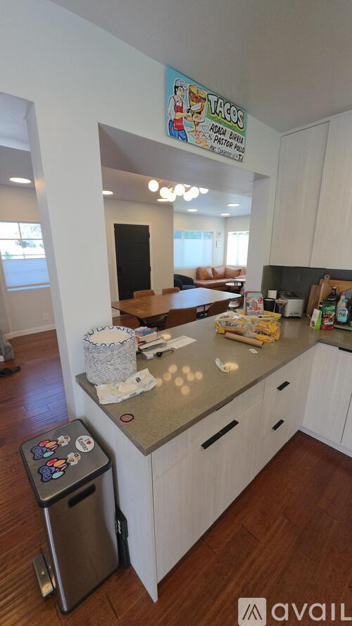 A kitchen with a trash can and a sign on the wall.