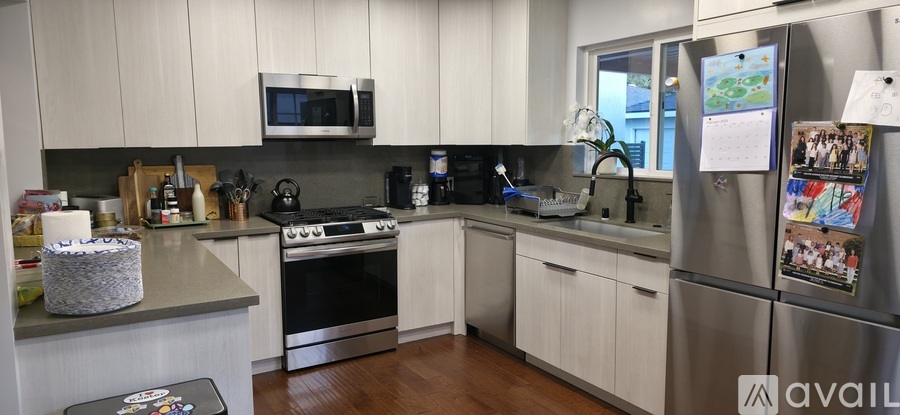 A kitchen with white cabinets and a refrigerator with a paper taped to it.