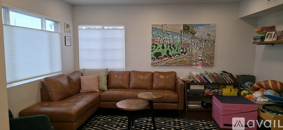 A living room with a brown leather couch and a painting on the wall.