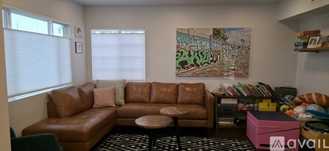 A living room with a brown leather couch and a painting on the wall.