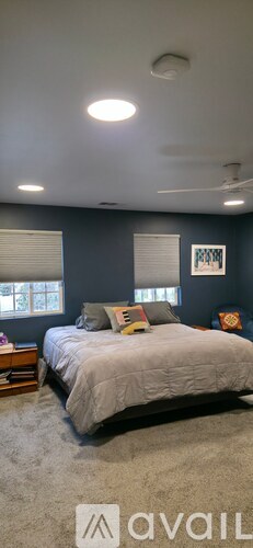 A bedroom with a bed, pillows, and a ceiling fan.
