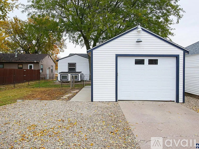 A white garage with a blue trim is situated in a residential area.