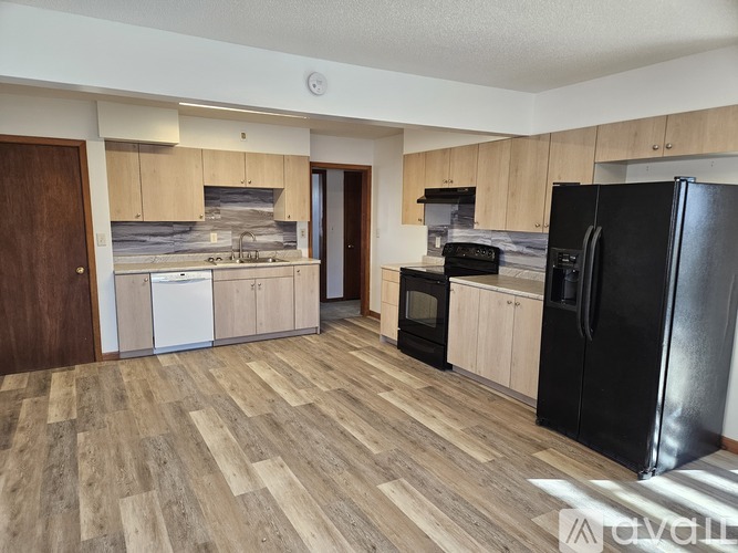A kitchen with black appliances and wooden floors.