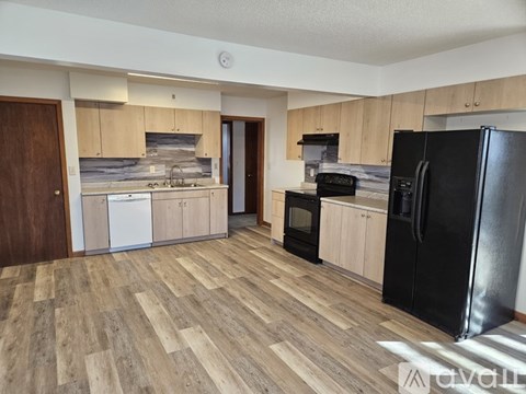 A kitchen with black appliances and wooden floors.