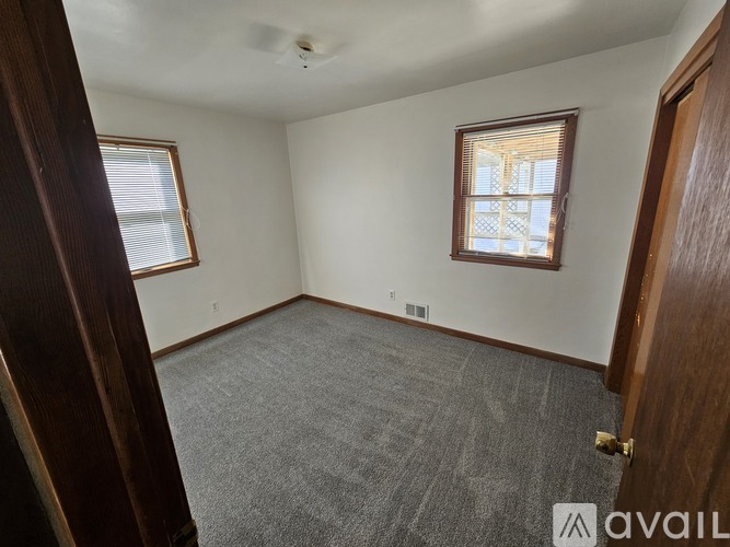 A room with a carpeted floor and a window with blinds.