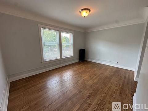 A room with wooden flooring and a window overlooking a green area.