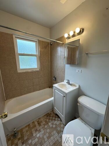 A bathroom with a tub, toilet, sink and mirror.
