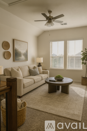 A living room with a beige couch, a coffee table, a ceiling fan, and a painting on the wall.