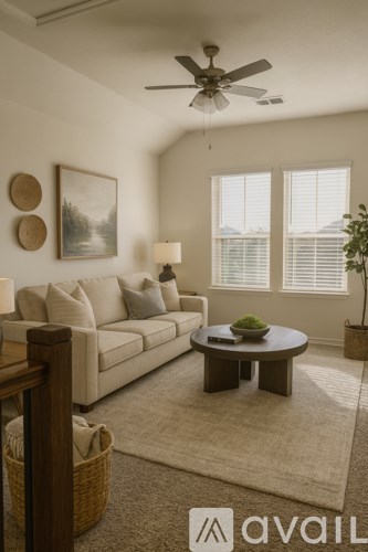 A living room with a beige couch, a coffee table, a ceiling fan, and a painting on the wall.