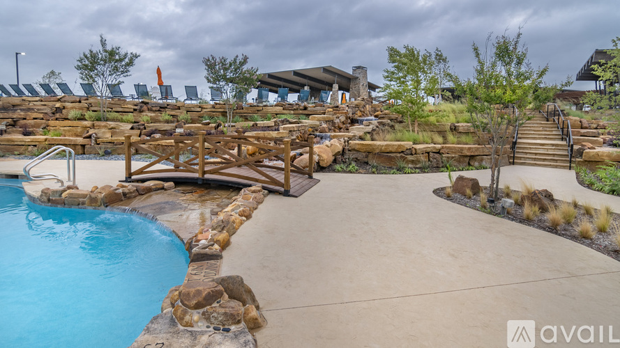 A pool surrounded by a stone wall and a wooden deck.