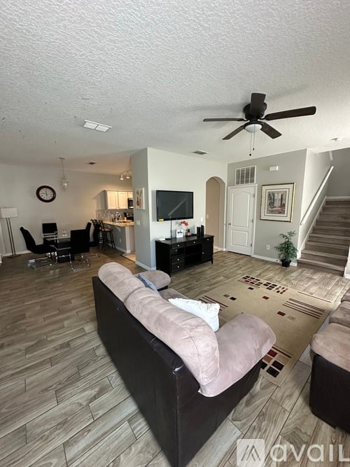 A living room with a couch, a television, and a staircase.