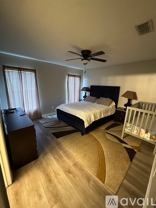 A bedroom with a bed, dresser, and ceiling fan.