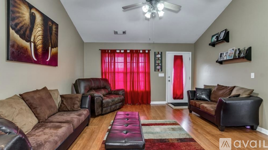 A living room with brown leather furniture and a painting of an elephant on the wall.