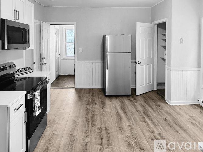 A kitchen with a black stove top oven, a black microwave, a black refrigerator, and a wooden floor.