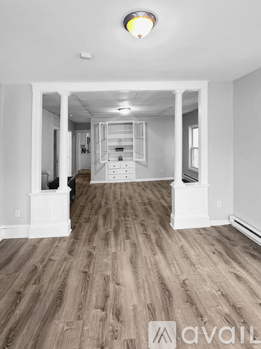A spacious room with wooden flooring and white walls.