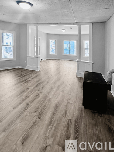 A room with wooden flooring and a piano in the corner.