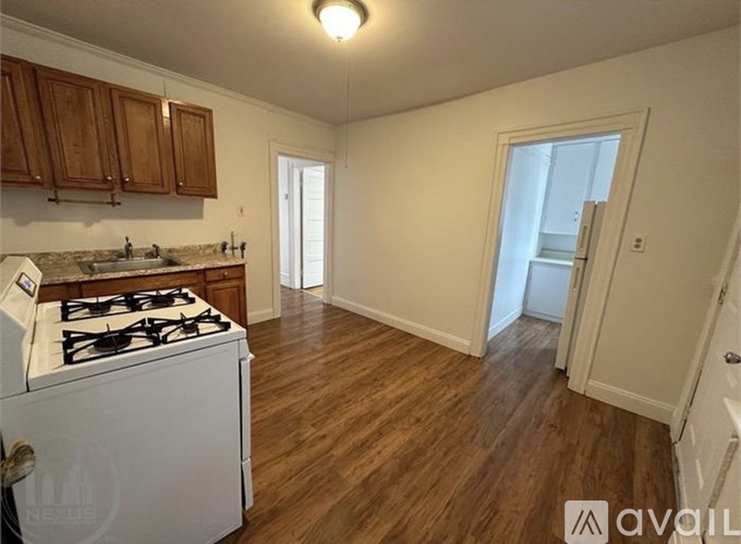 A kitchen with a white stove top oven and wooden cabinets.