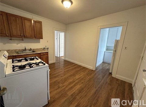 A kitchen with a white stove top oven and wooden cabinets.