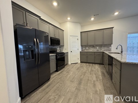 A kitchen with a black refrigerator and a white door.