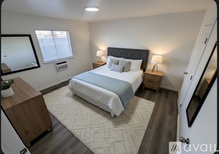 A bedroom with a bed, nightstand, and a mirror on the wall.