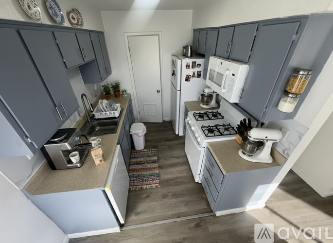 A kitchen with a white fridge, white microwave, and a white stove.