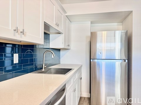 A kitchen with white cabinets and a blue tile backsplash.