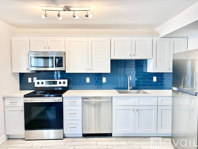 A kitchen with white cabinets and a blue backsplash.