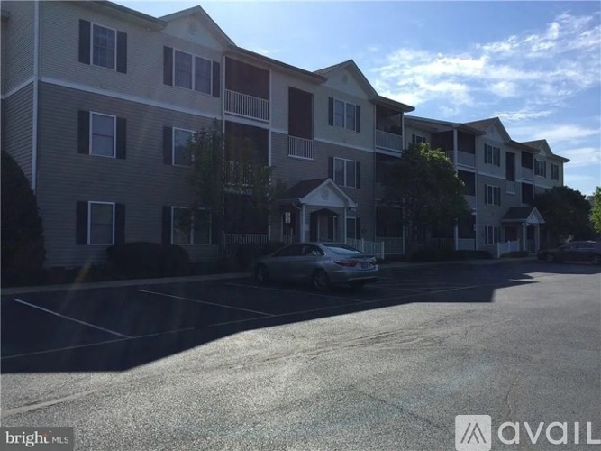 A car is parked in front of a building with a balcony.