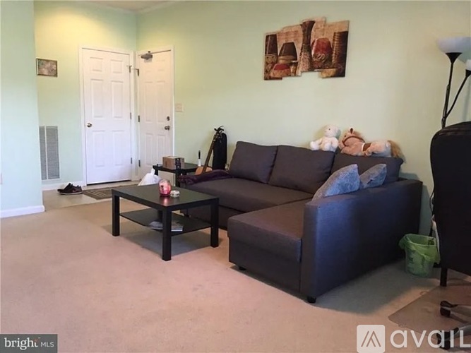 A living room with a couch, coffee table, and a couple of doors.