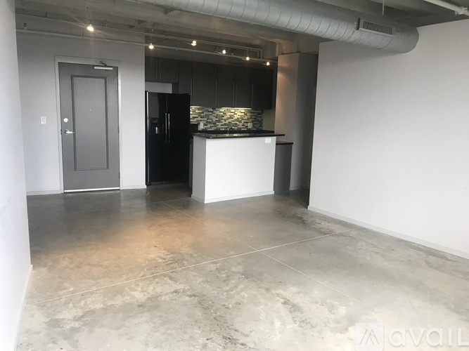 A spacious room with a kitchenette and a door on the left.