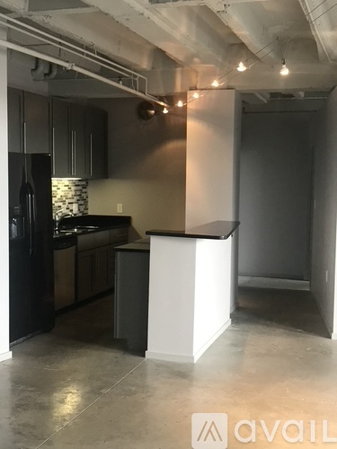 A kitchen with a black refrigerator and a white island.