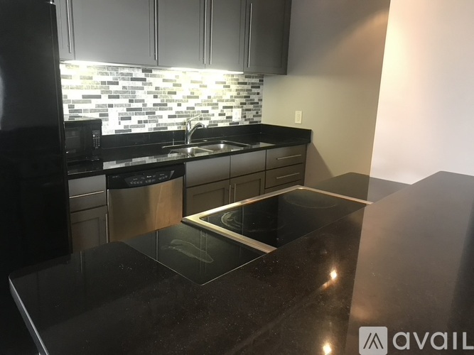 A kitchen with black countertops and a backsplash of square tiles.
