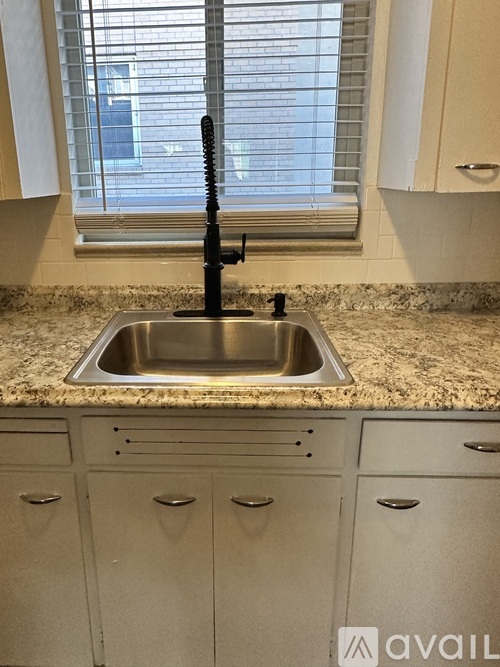 A kitchen sink with a black faucet and a window above it.