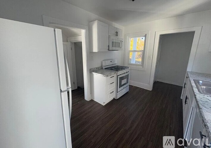 A kitchen with white appliances and wooden floors.